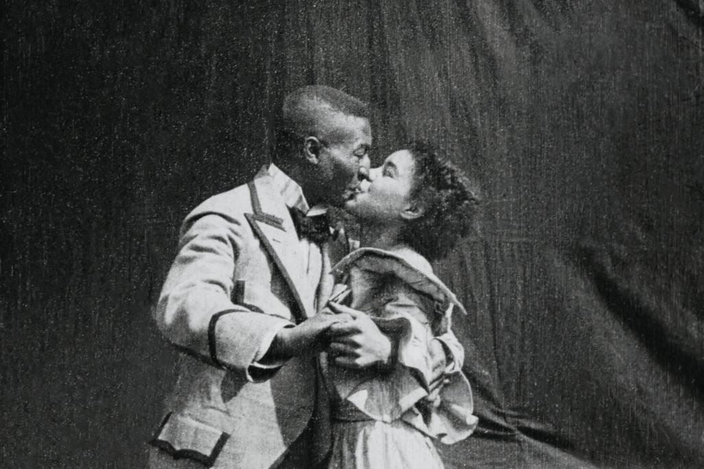 Black and white image of a black man and a black woman kissing