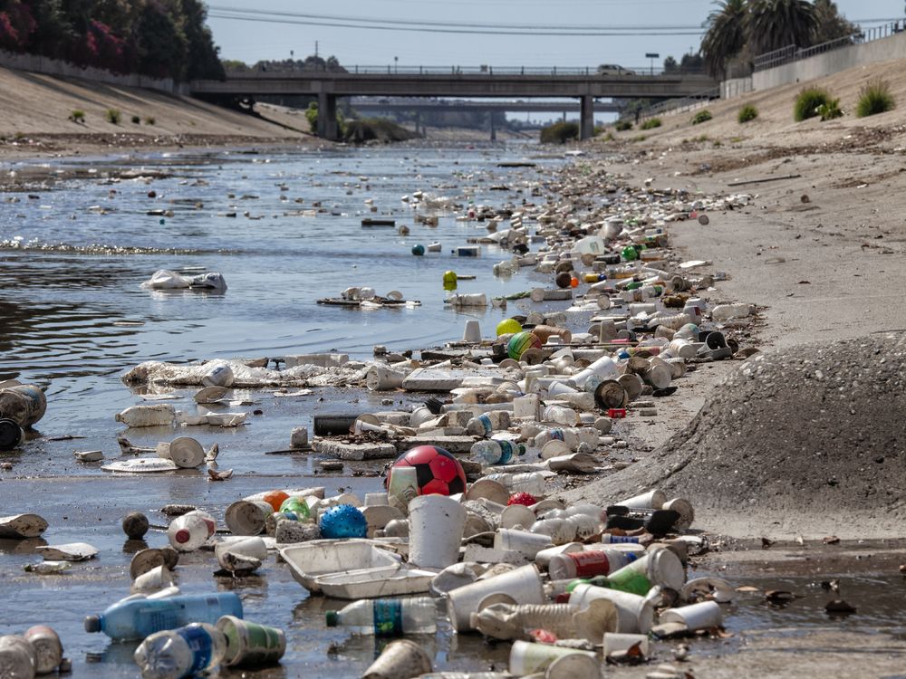 Large amounts of plastic trash like bottles in a channelized creek in Culver City, California.