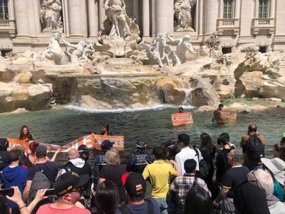 Protesters hold signs during the demonstration in Rome&#39;s Trevi Fountain.