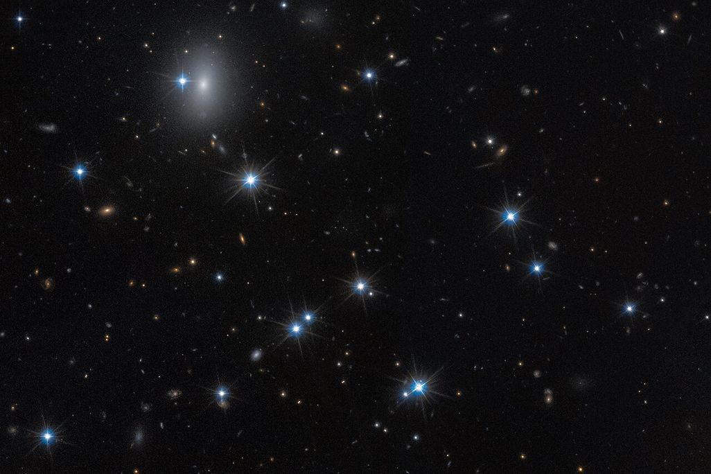 image of space with bright stars and yellow galaxies