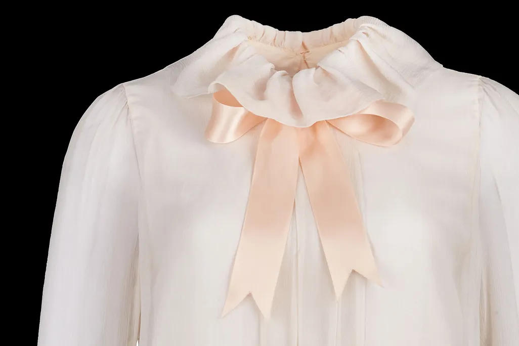 Close-up shot of blush pink blouse with a ribbon tied in a bow