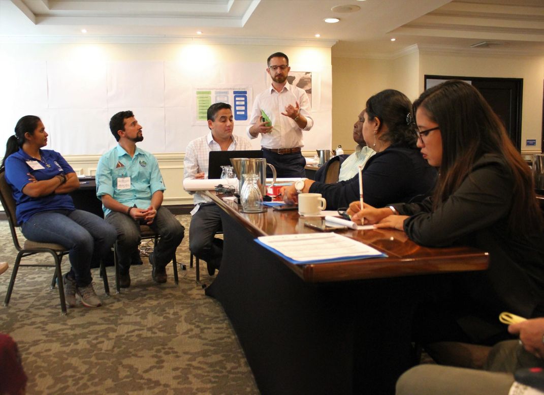 A group of people sitting at a table in a conference room.