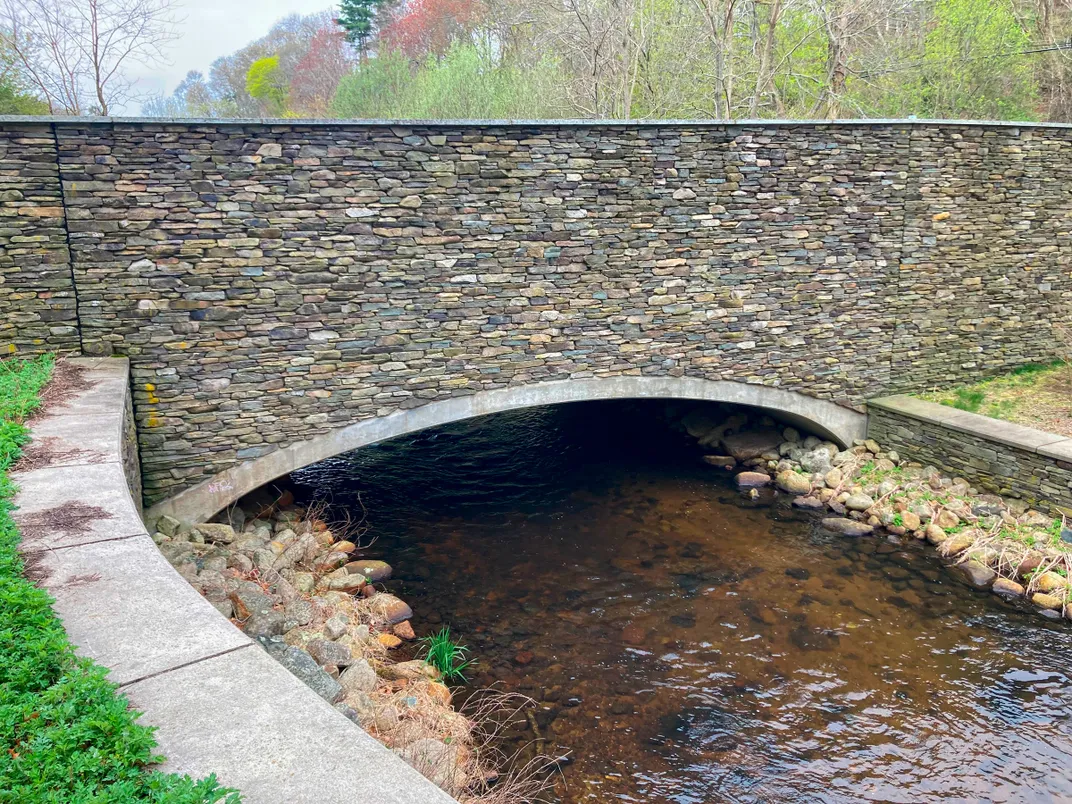 a stone bridge goes over a narrow river