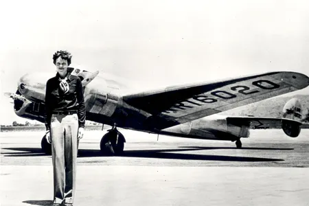 Ameila Earhart standing in front of the Lockheed Electra in which she disappeared in 1937.