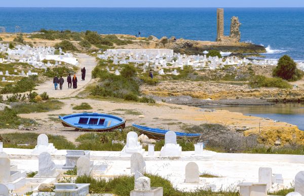 A family of Tunisian tourists crosses an old cemetery to go to the beach. thumbnail