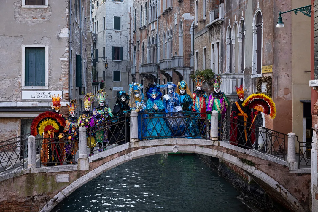 costumed people stand on an arched bridge