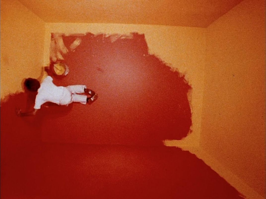 A photograph from above of a man painting a room.