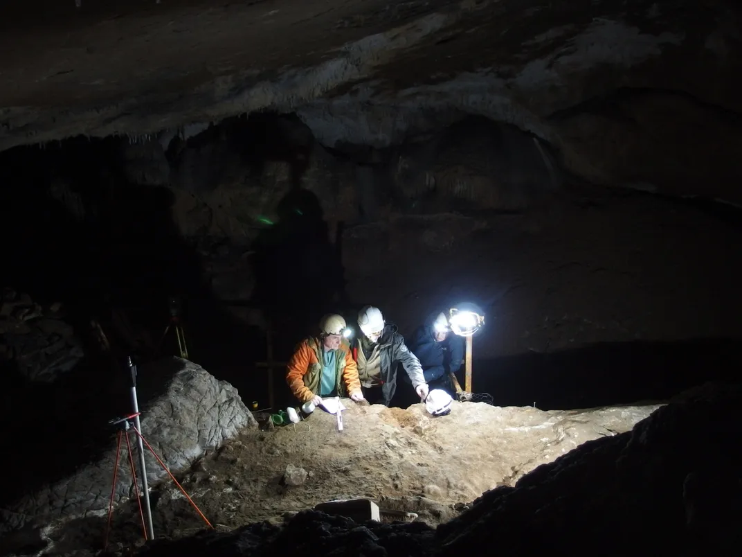 three people wearing hard hats and headlamps look at rock in the dark