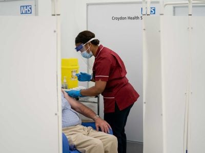 A nurse administers the Pfizer-BioNTech COVID-19 vaccine to a patient in London on December 8. Some experts say the fastest way to test second-generation COVID-19 vaccines is through human challenge trials. 