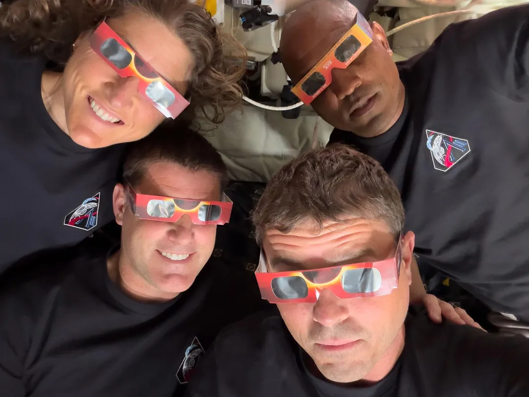 the four crew members of Artemis 2 wear eclipse glasses. two are smiling