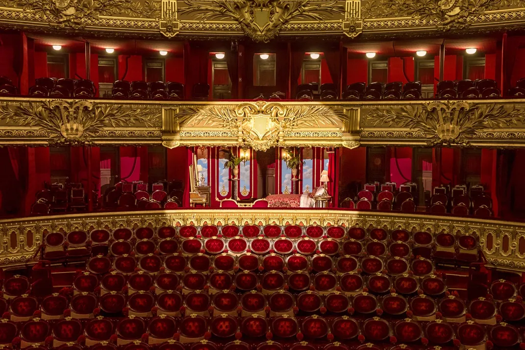 Spotlight on lavish red opera house box with a bed inside