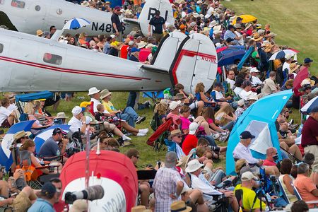 At AirVenture in Oshkosh, Wisconsin, airplane fans have found a good spot by a brace of twin-tailed classic aircraft to watch the airshow.