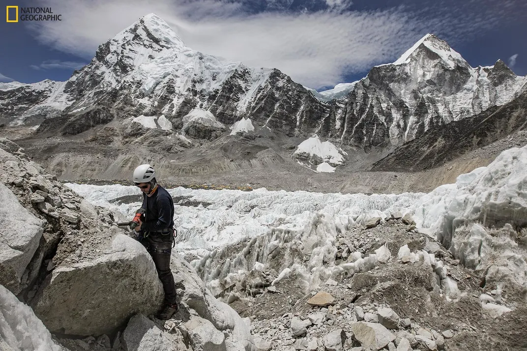 A member of the National Geographic and Rolex Perpetual Planet Everest Expedition team takes a sample from a rock outcrop next to the Khumbu Icefall above Everest Base Camp. 