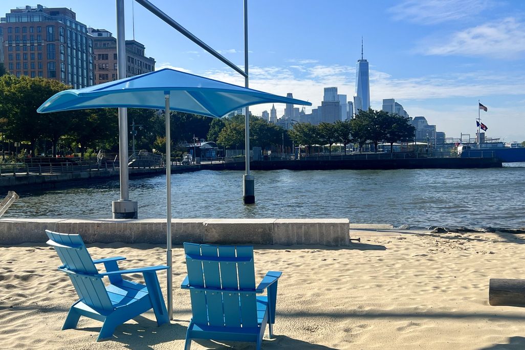 Blue beach chairs on sand with blue umbrella