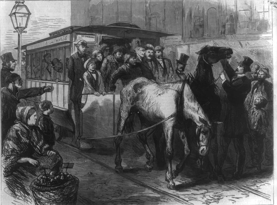 Man in top hat touching horse pulling a streetcar, as a tired horse droops its head