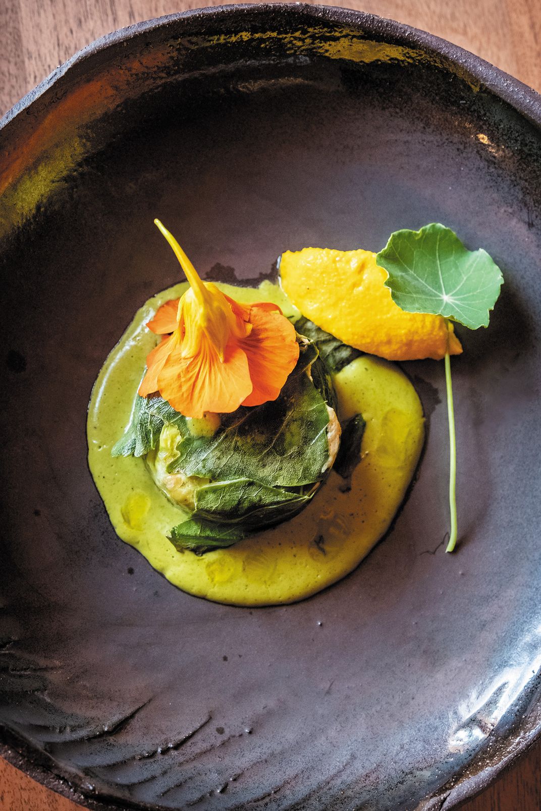 smoked trout with garlic and nasturtium, wrapped in kale, served atop nettle cream with carrot cream on the side.