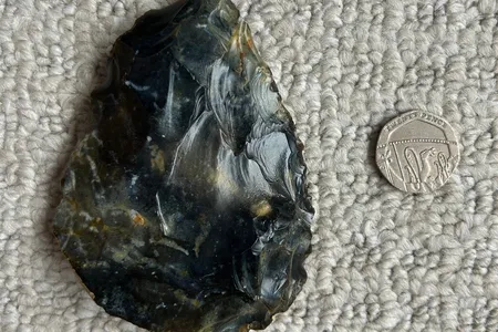 The hand ax, seen here beside a 20-pence coin, is between 40,000 and 60,000 years old.
