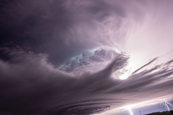 An ominous nighttime cyclonic cloud cradling a mass of lightning thumbnail