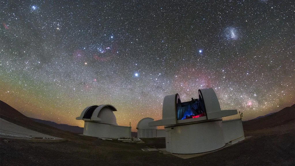 A pair of telescopes in the Atacama Desert in Chile gaze up at a starry night sky.