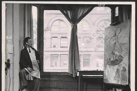 Yasuo Kuniyoshi, in his New York City Studio in 1940, is at work on the painting Upside Down Table and Mask, currently on view at the Smithsonian American Art Museum.