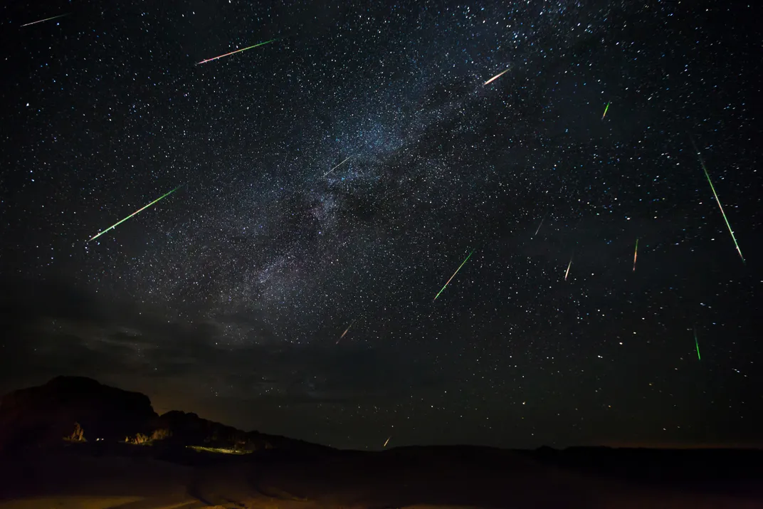 A photo of the night sky shows the visible Milky Way and many meteors 