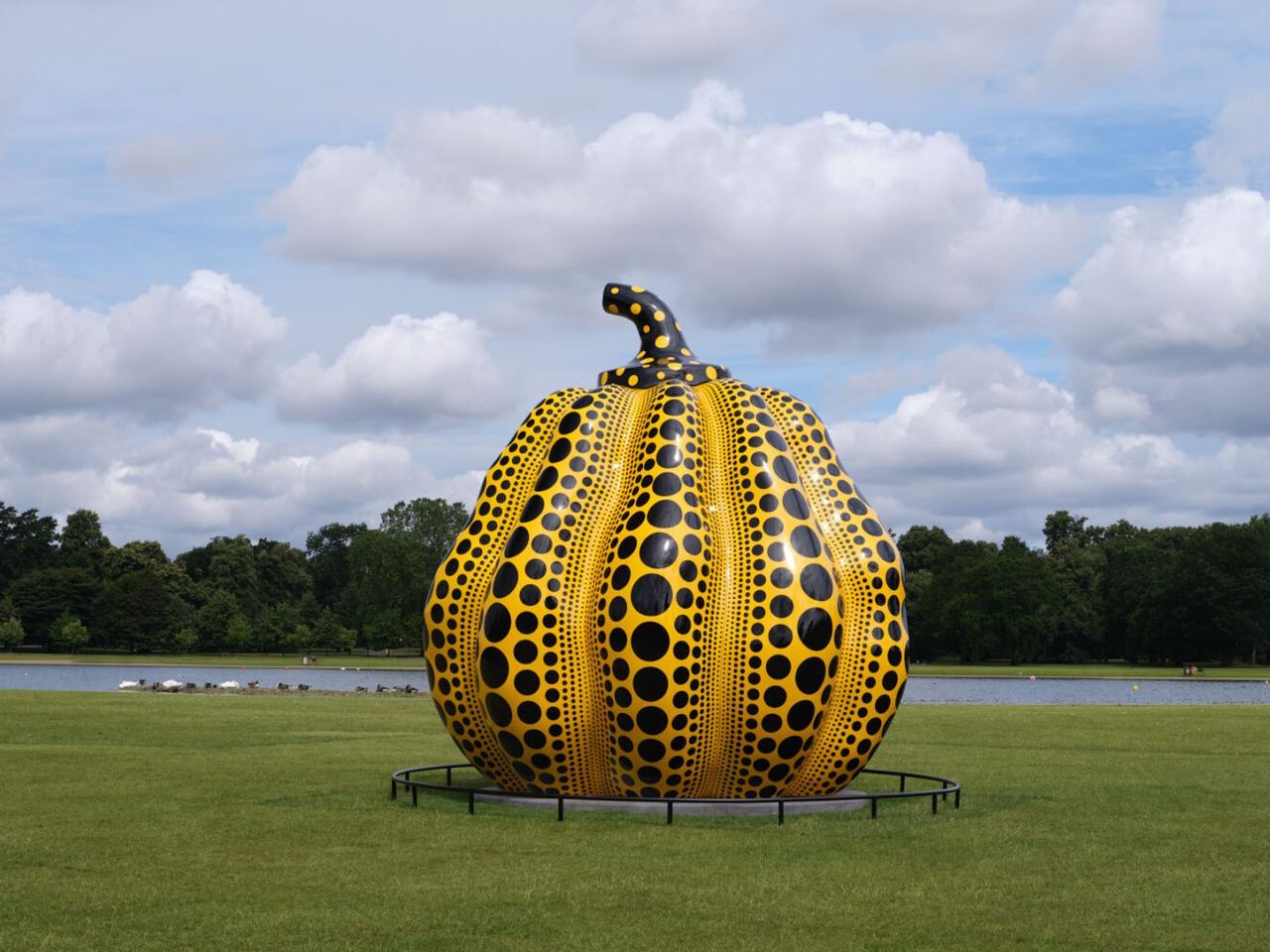 The bronze Kusama Kensington Gardens pumpkin, yellow with black polka dots, stands six metres tall on the grass beside the Round Pond in 2024.
