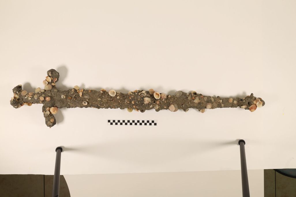 A sword covered in sediment and shells