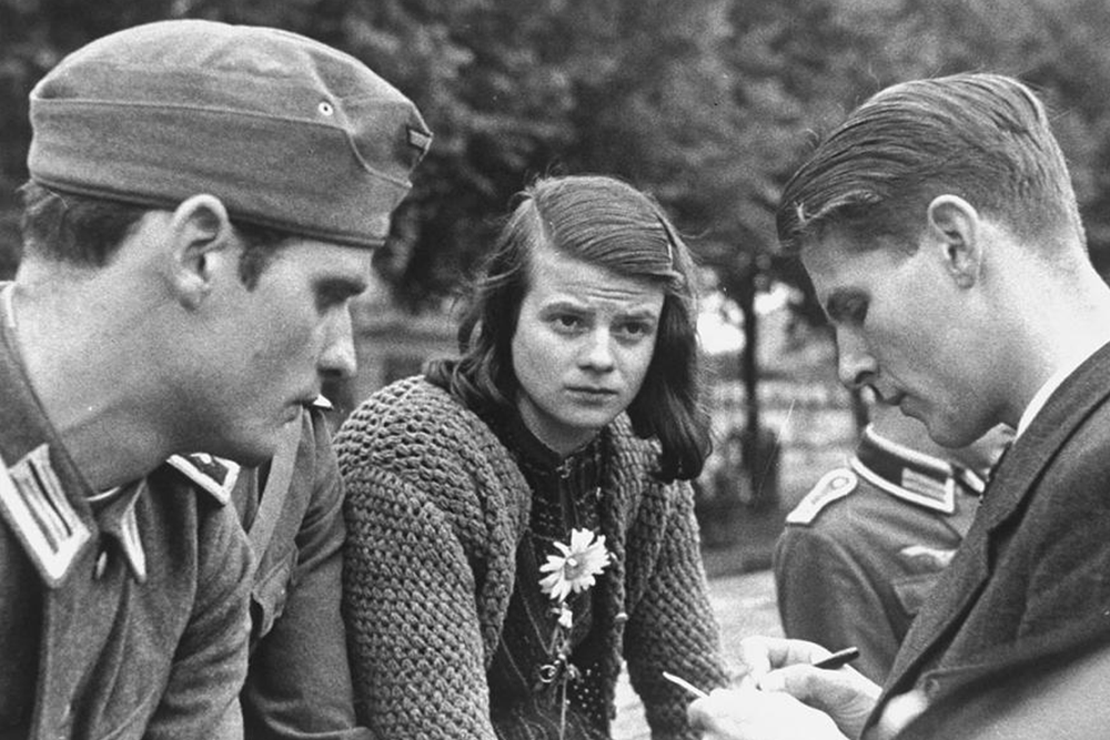 Sophie Scholl (center) bids farewell to her brother Hans (left) and their friend Christoph Probst (right) as they depart for the Eastern Front in July 1942.