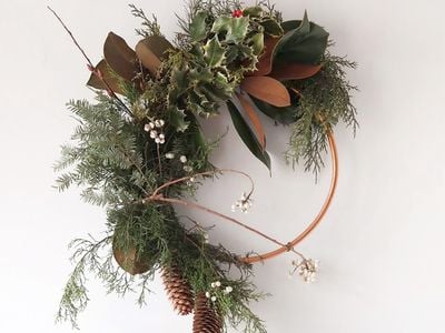 A modern evergreen wreath on a metal hoop displayed on a white background
