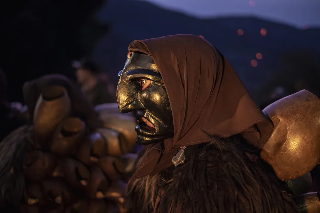A Mamuthone circles a fire at twilight.