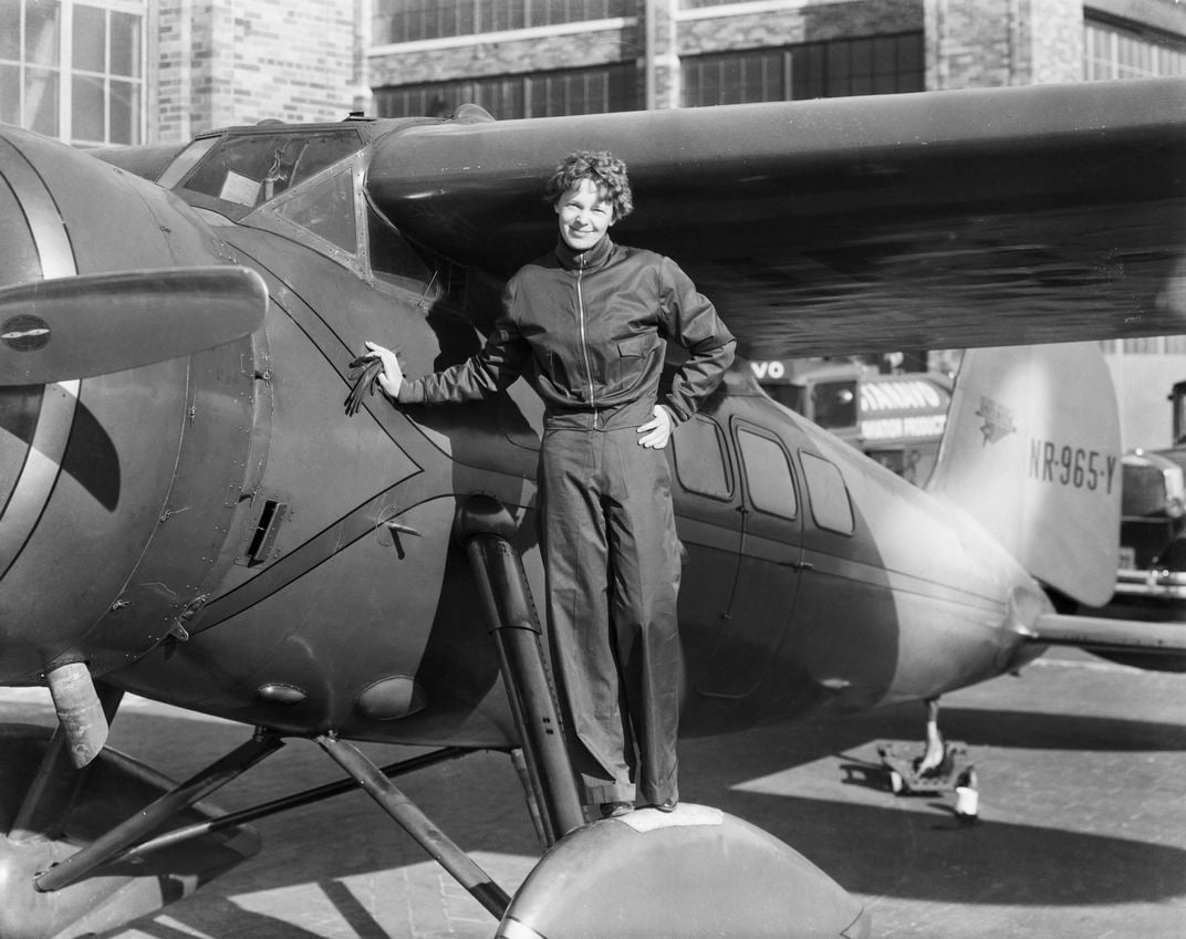 Woman in a jumpsuit standing next to plane