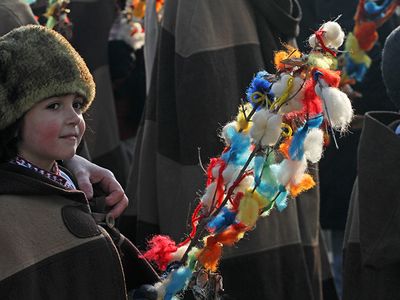 A young girl lightly pats the backs of others with a survachka on Christmas Day in Bulgaria.