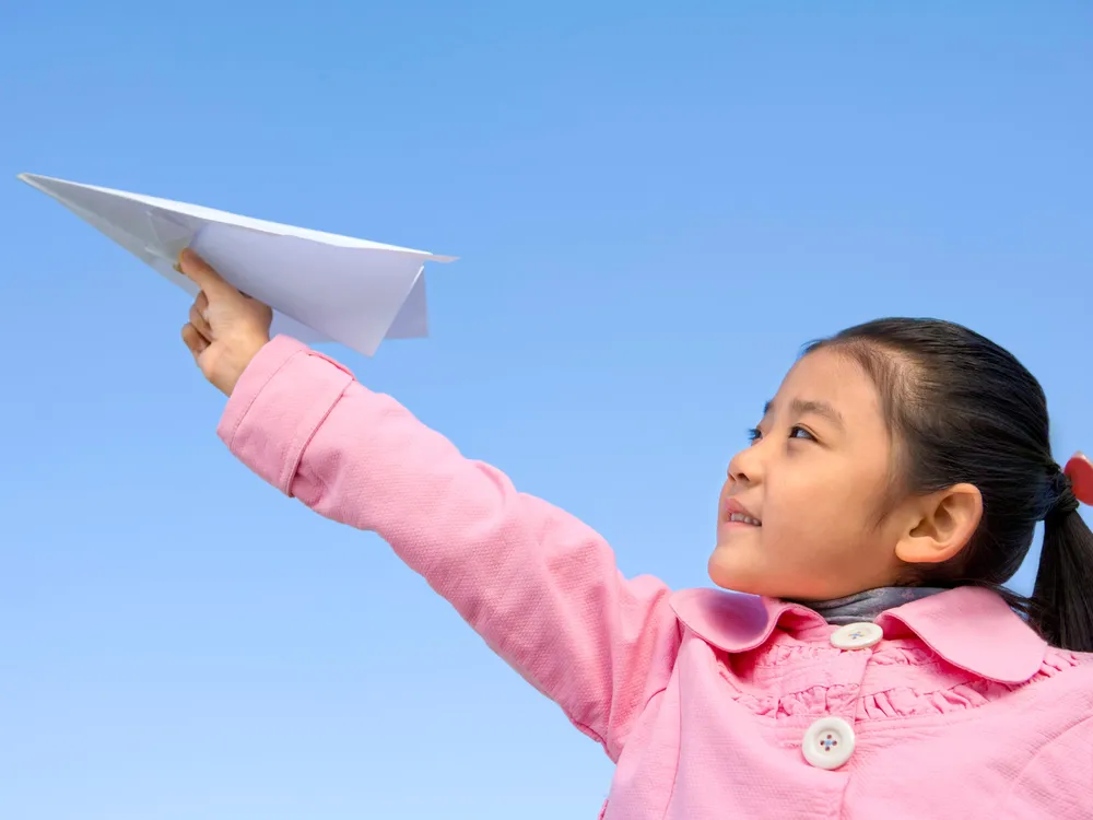 girl throwing paper airplane