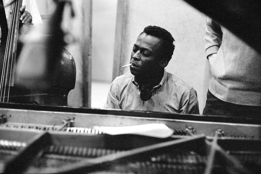 Miles Davis smoking a cigarette while playing the piano