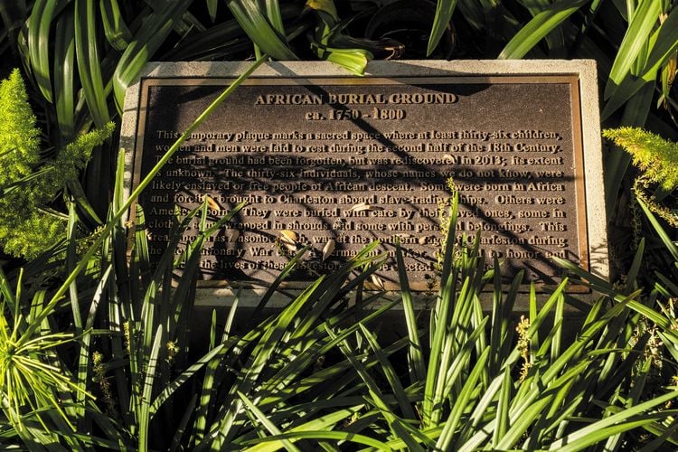 a plaque surrounded by grass honoring the spot where a mass grave was found