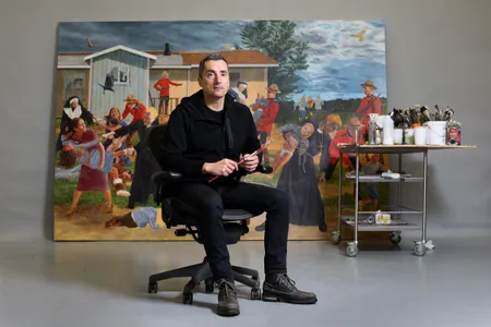 Kent Monkman, a Canadian artist of Cree ancestry, poses with one of his large-scale history paintings, The Scream.