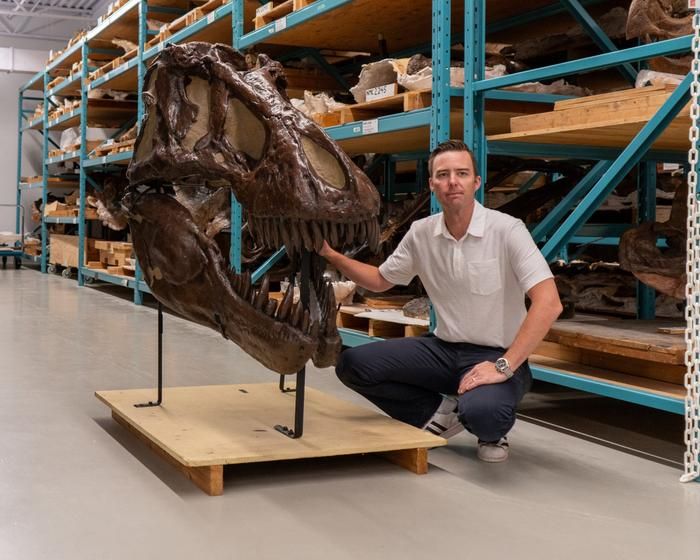 Dr. Jordan Mallon beside the cast of a T.rex skull