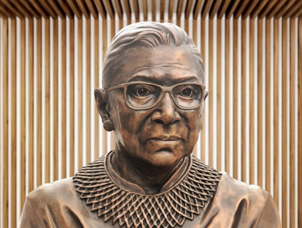 A close up of the bronze sculpture of RBG's face, with her distinctive collar and square glasses