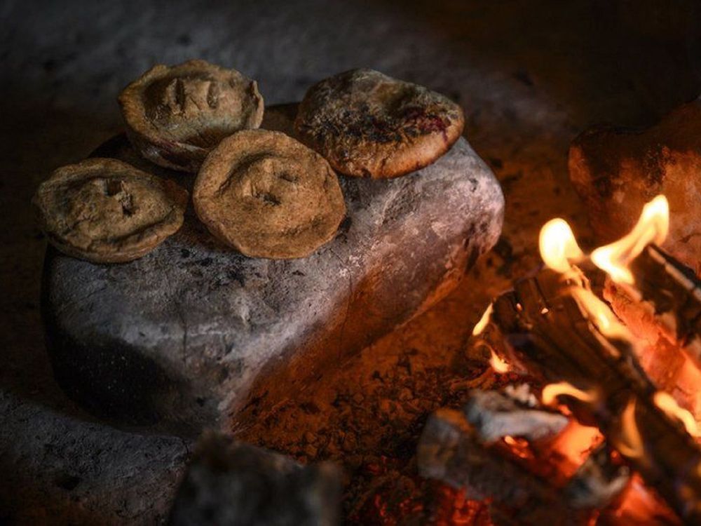 small pies cooking on hot stone by fire