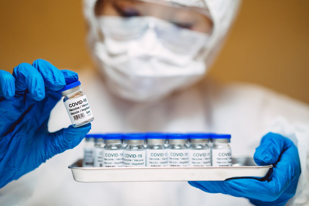 A staged stock image of a healthcare worker holding a tray of generic Covid-19 vaccines