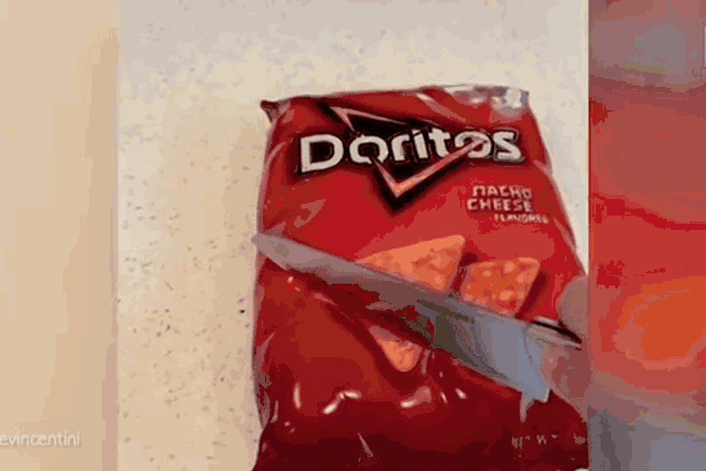 Gif of someone cutting into a bag of Doritos that is actually a cake