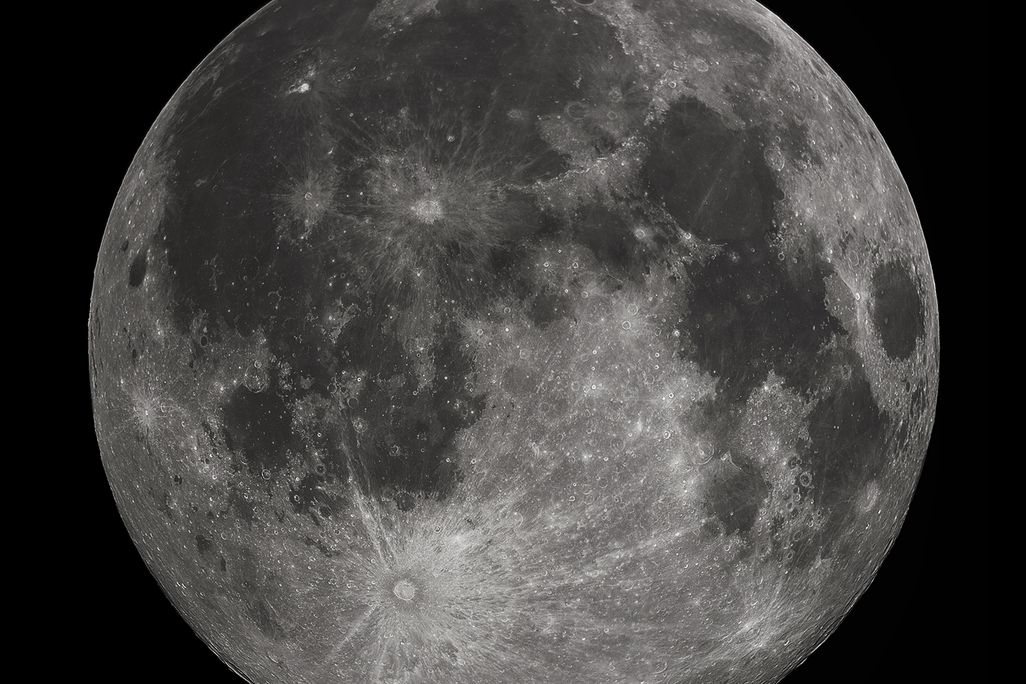 An image of a full moon. The moon looks silver with grey sploches.