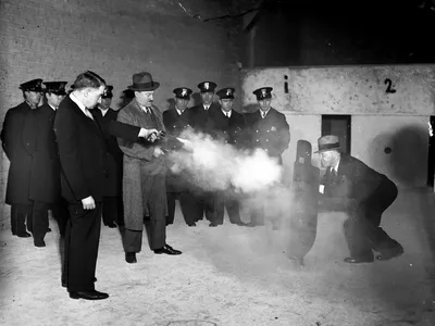 Lts. Frank Ballou and Samuel Peterson test out a new metal bulletproof shield. The shield's inventor, Elliot Wisbrod, is the man holding it. 