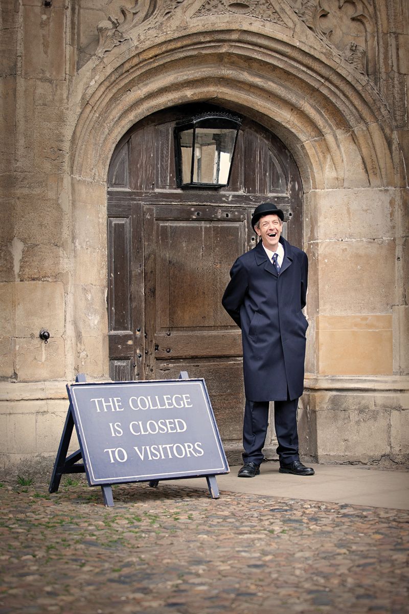Man stands beside a sign that says "the college is closed to visitors"