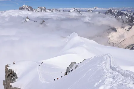 Alpinists ascend along a narrow ridge of ice and snow in the Mont Blanc massif.