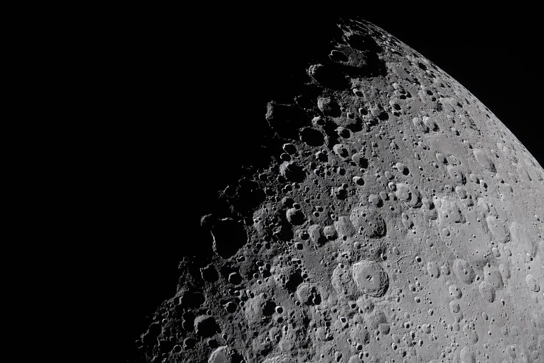 a close-up view of the moon's cratered surface, with half of the image in darkness