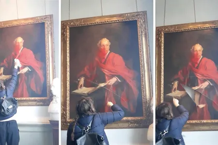 A video posted on social media shows a woman spraying red paint on the portrait, then cutting it with a handheld tool.