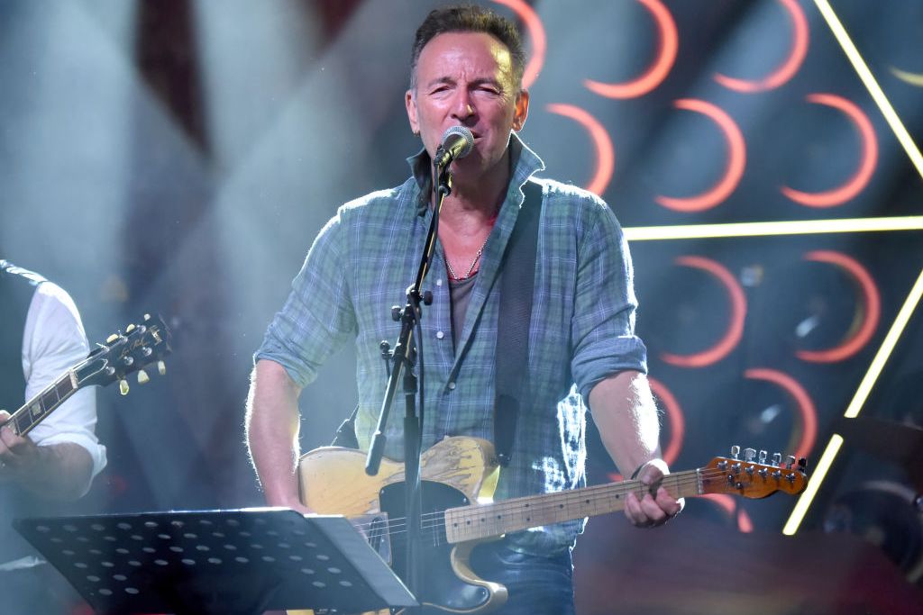 middle-aged man singing on stage into microphone and playing