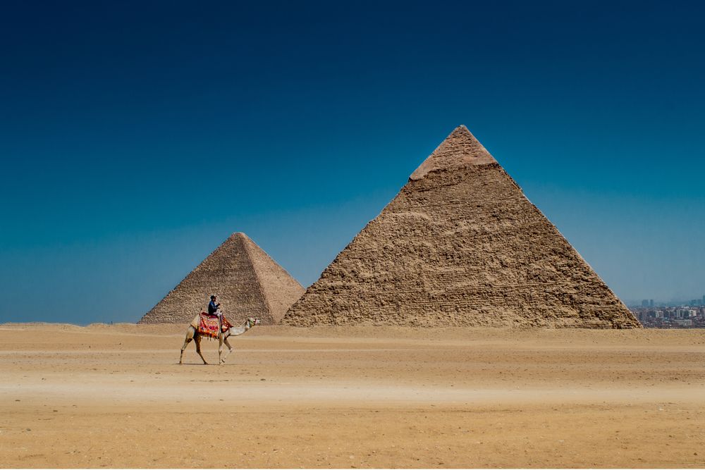 OPENER - A man rides a camel in view of the remarkable Egyptian pyramids.