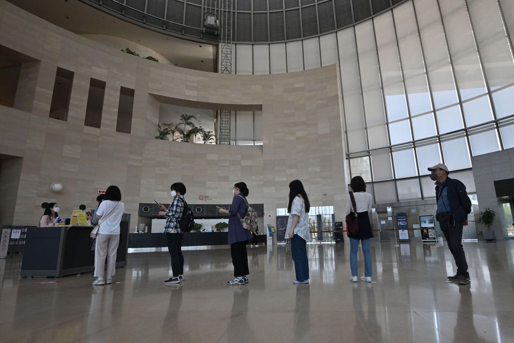 Visitors wearing face masks wait in line to enter an exhibition hall at the National Museum of Korea in Seoul on May 6, 2020. 